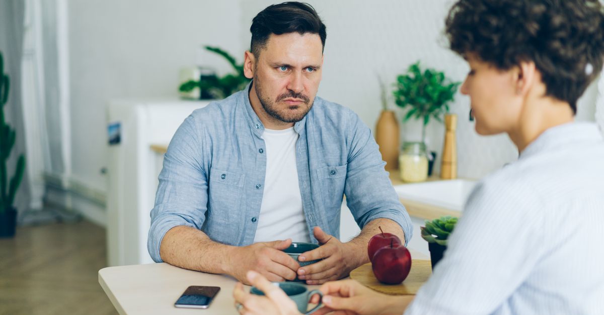 Dos personas conversando en una mesa de reuniones con documentos